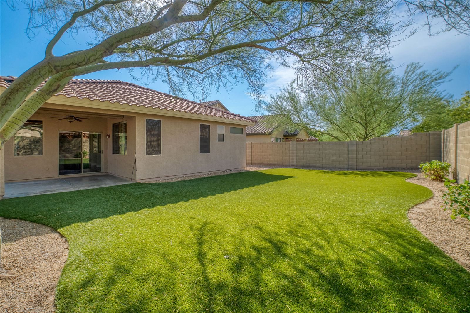Backyard with fresh sod, clean gravel beds, and a tidy patio