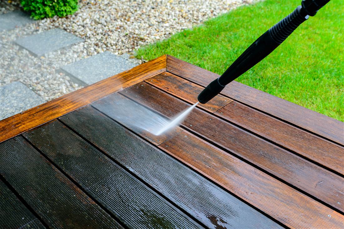 Pressure washer cleaning a wooden deck, half clean and half dirty